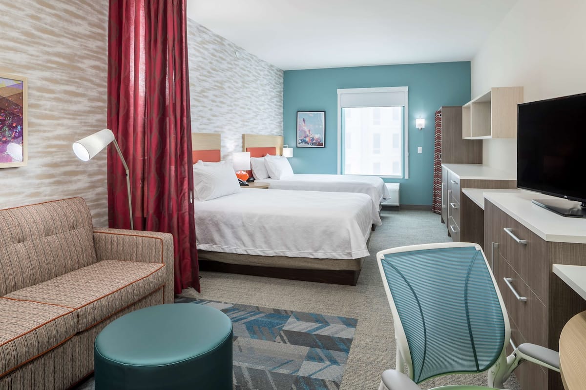 Une chambre d’hôtel avec deux lits, un canapé, un bureau, une télévision et une fenêtre.