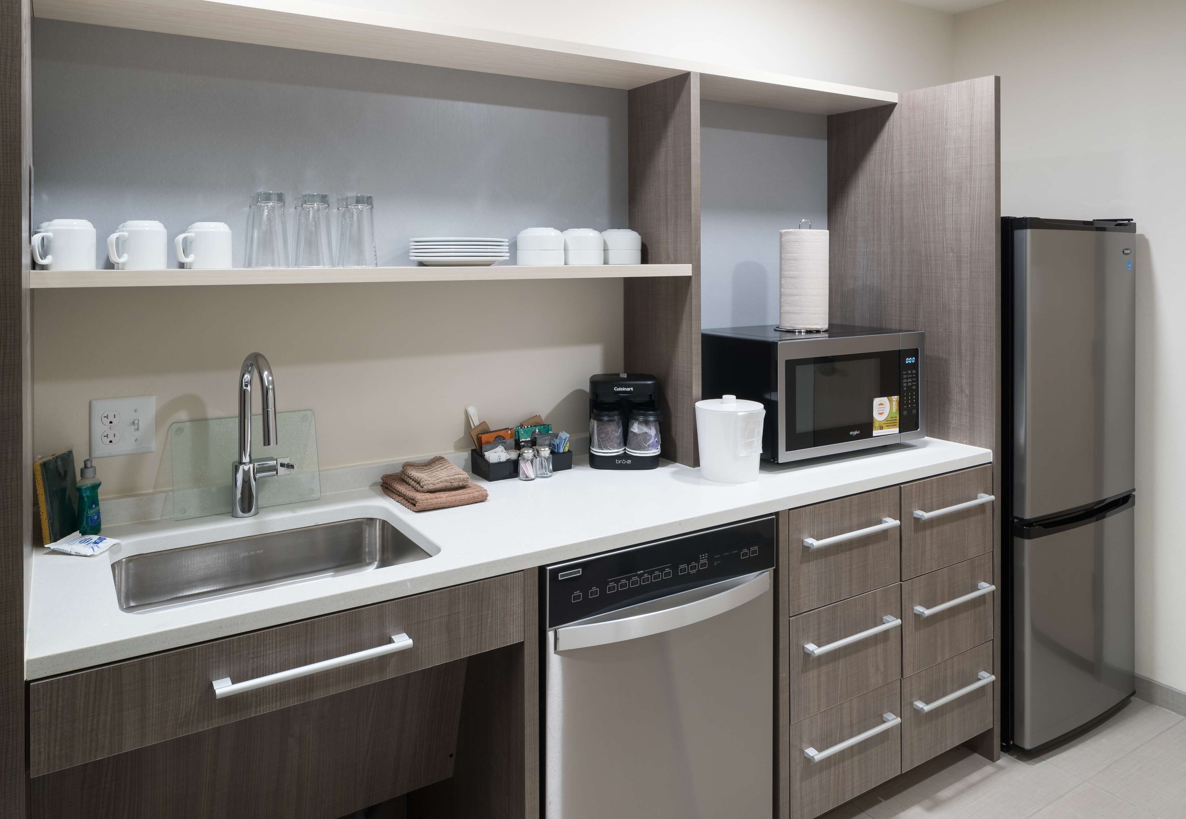 A modern kitchen with a dishwasher, a refrigerator, a microwave, and a sink.