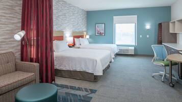 A hotel room with two beds, a desk, a chair, a lamp, and a window.