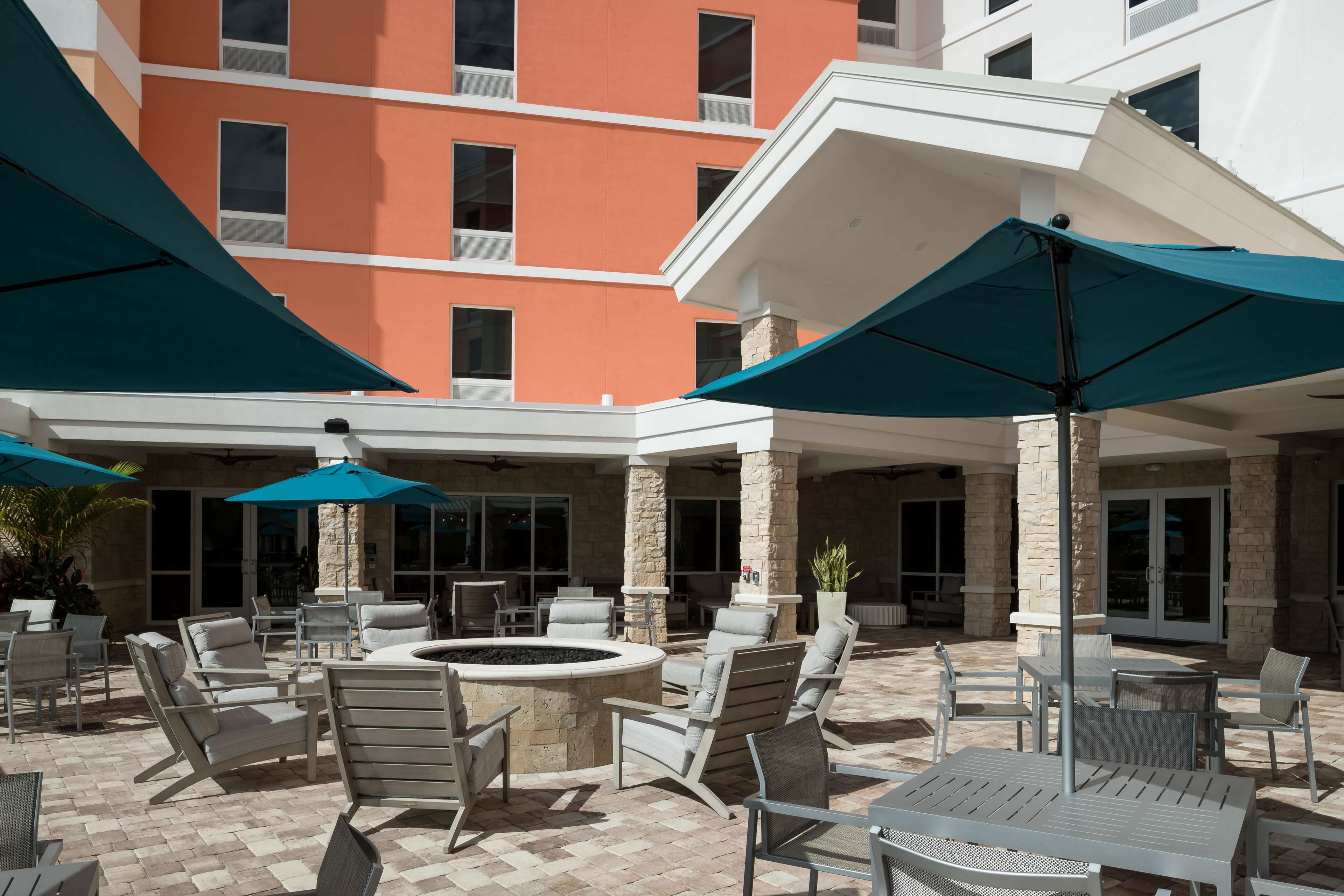 A hotel courtyard with outdoor seating, a fire pit, and umbrellas.