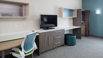 Una habitación de hotel moderna con escritorio, televisión y armario.