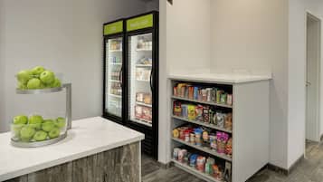 Una kitchenette con encimera de mármol, una presentación de frutas, un refrigerador con etiquetas que dicen 'frío' y 'muy frío', y una alacena con diversos alimentos.