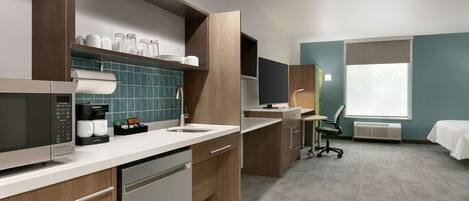 A modern kitchen with a microwave, coffee maker, and a sink. There is a window with a view of the outside.
