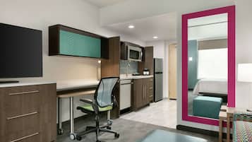 A modern kitchen with a microwave, refrigerator, and a dining area with a table and chairs.