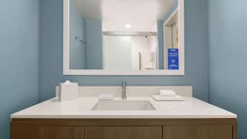 A bathroom with a white sink, a large mirror, and wooden cabinets.