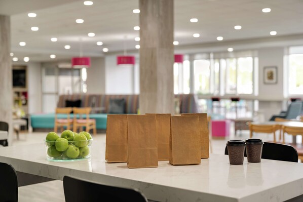 Un interior moderno con encimera de mármol, un bol de manzanas verdes y bolsas de papel sobre una mesa.