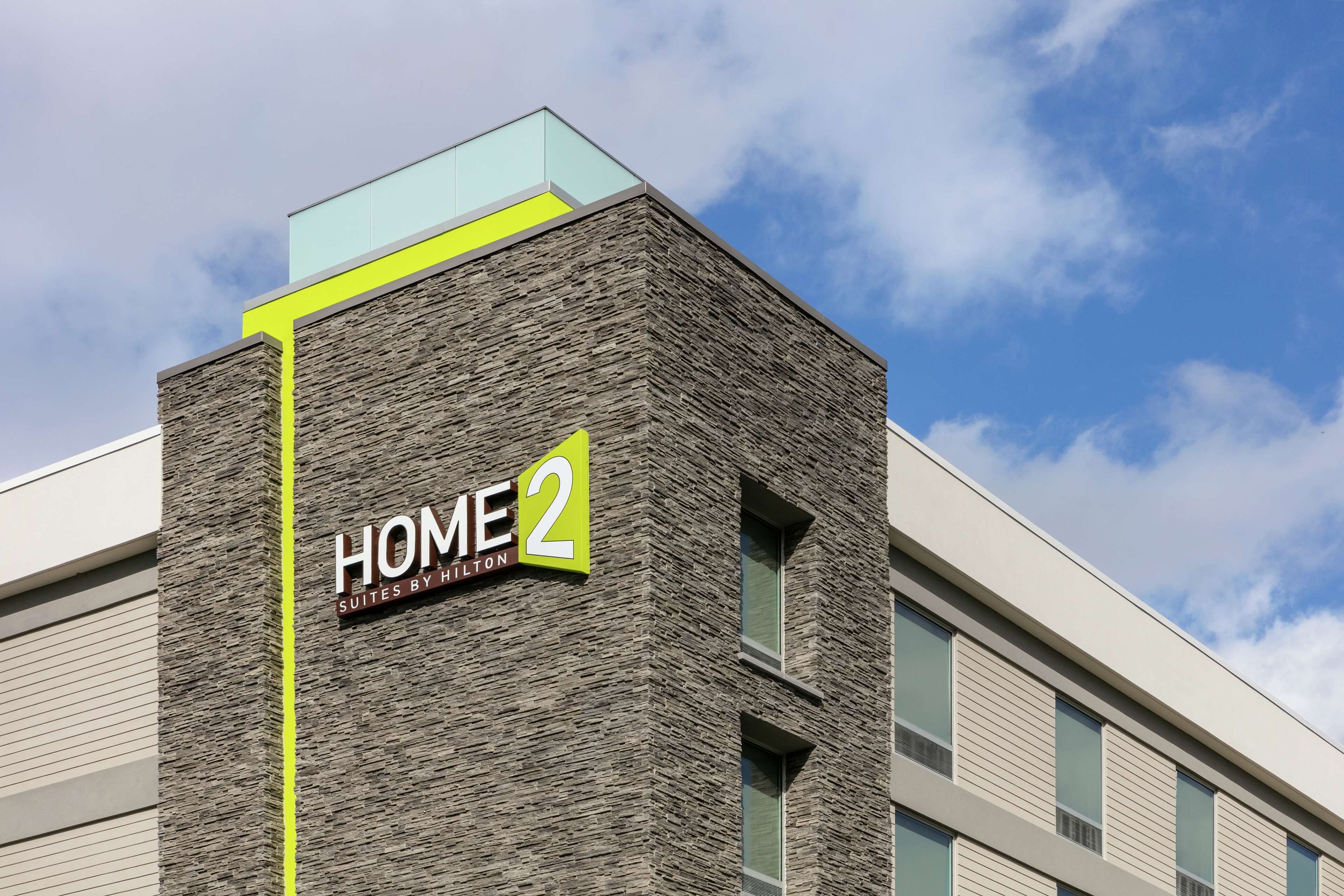 A building with a sign reading "HOME 2 Suites by Hilton" on a textured facade.
