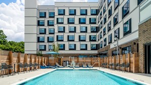 Un hotel moderno con piscina, varios balcones y zonas de estar al aire libre.