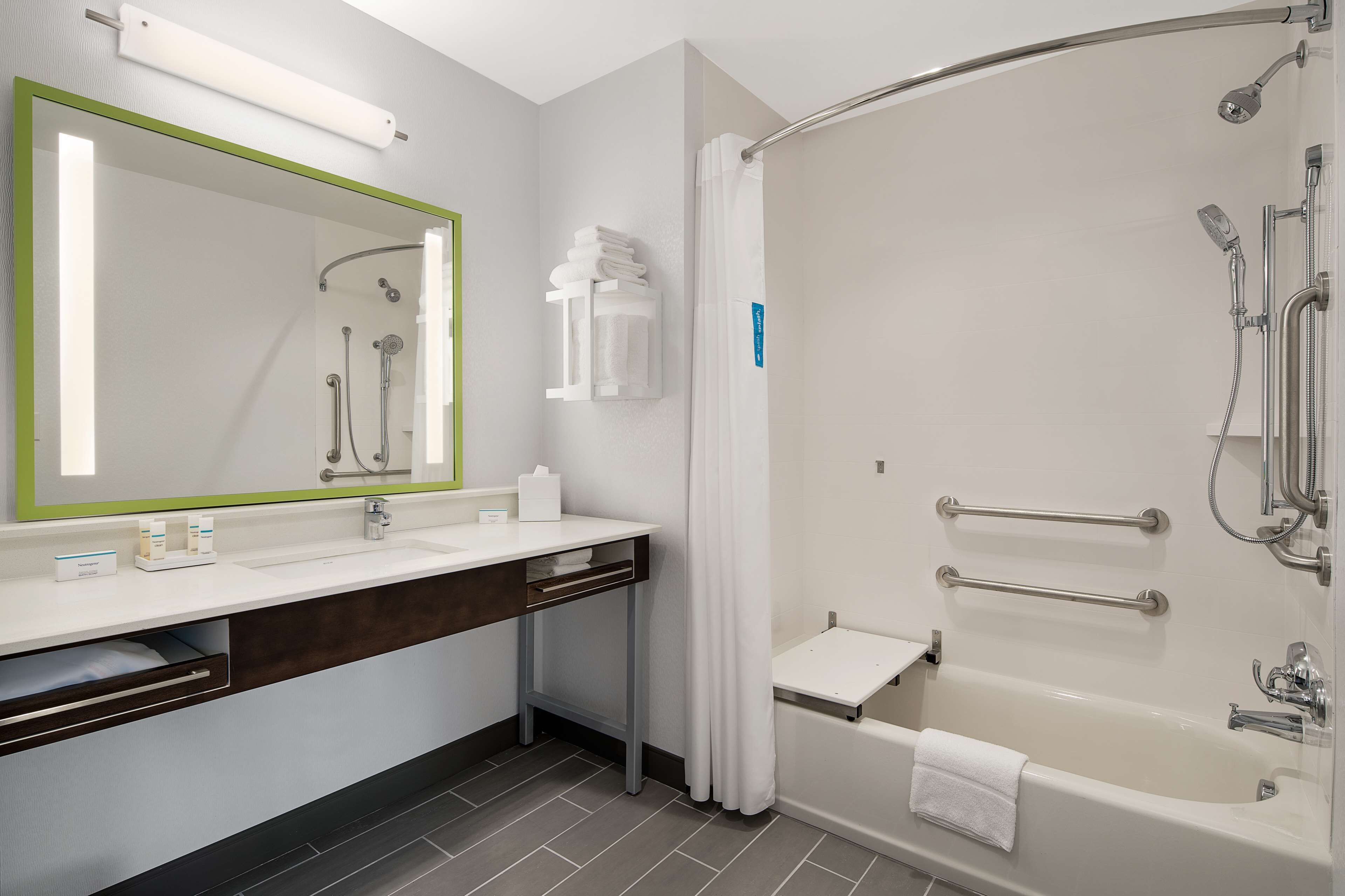 Une salle de bain moderne avec un grand miroir, un lavabo, une douche avec une porte en verre et une baignoire.