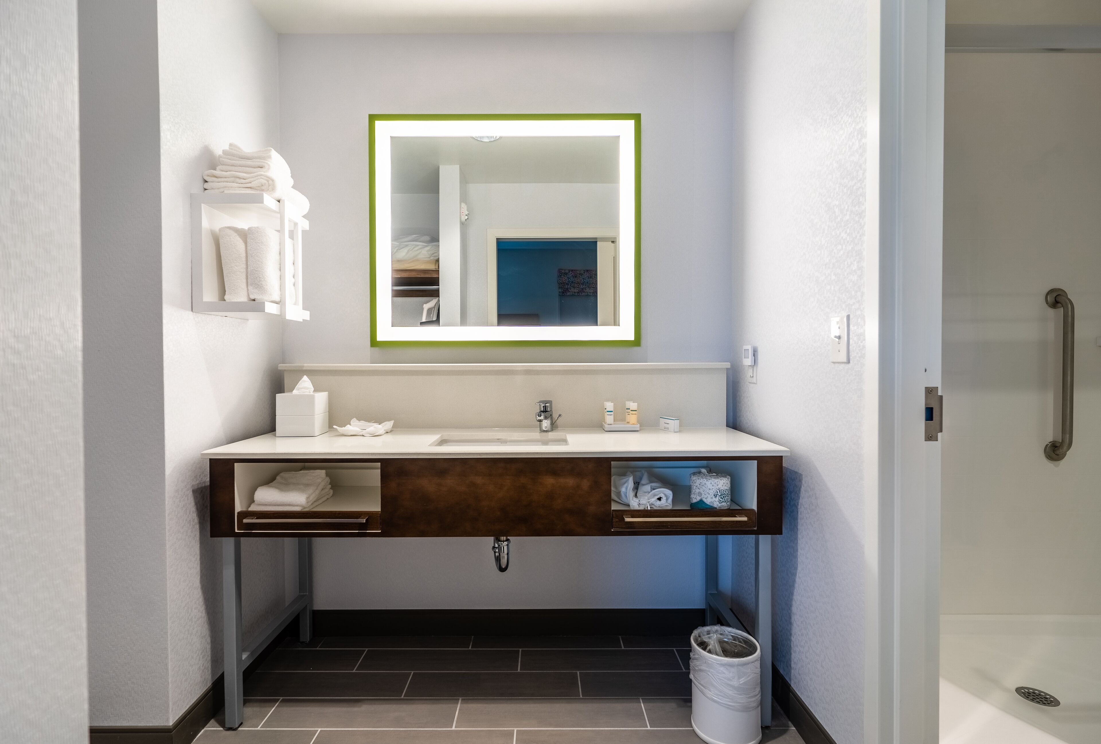 Un baño moderno con tocador, espejo, toallero y cabina de ducha.
