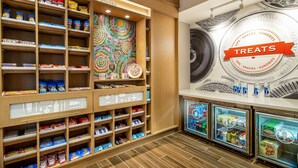 Un área de exhibición de aperitivos con estantes de diversas opciones y una sección refrigerada.