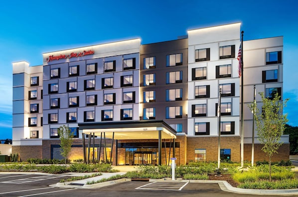 A Hampton Inn & Suites hotel with a modern facade, multiple floors, and a well-lit entrance.