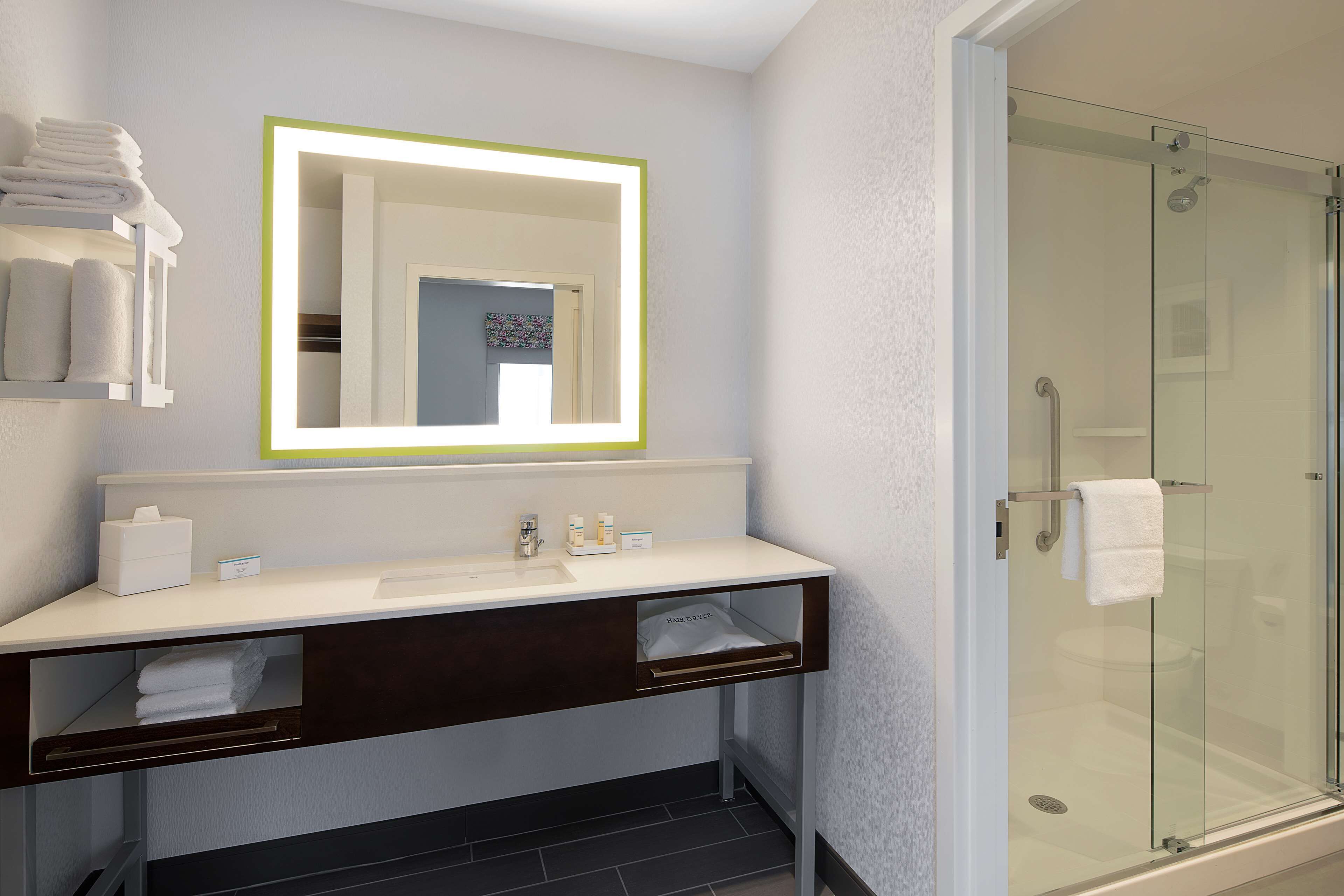 A modern bathroom with a glass shower enclosure, a vanity with a mirror, and neatly folded towels.