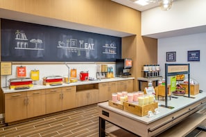 A breakfast bar with various food items and a chalkboard menu.