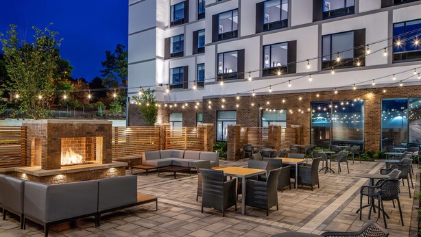 Un patio al aire libre con asientos, una chimenea y luces colgantes.
