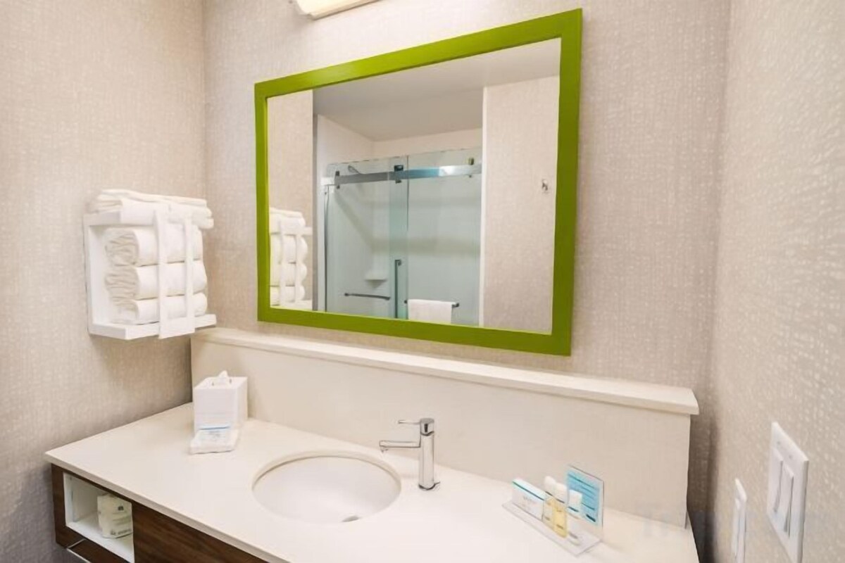 A bathroom with a sink, mirror, and towel rack.
