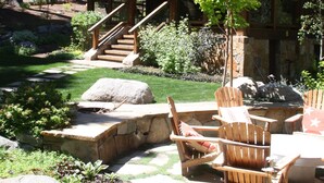 A wooden cabin with a stone staircase leading to a covered porch, surrounded by a well-maintained garden with rocks and plants. - Stunning Private Compound with Hot Tub, Nearby Beach, Flat Lawn, at ski resort (Homewood)