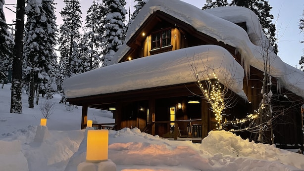 A log cabin with a snow-covered roof, surrounded by snow-covered trees. - Stunning Private Compound with Hot Tub, Nearby Beach, Flat Lawn, at ski resort (Homewood)