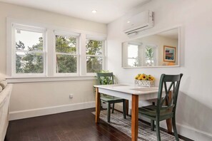 A dining area with a table, chairs, and a window with a view of trees.