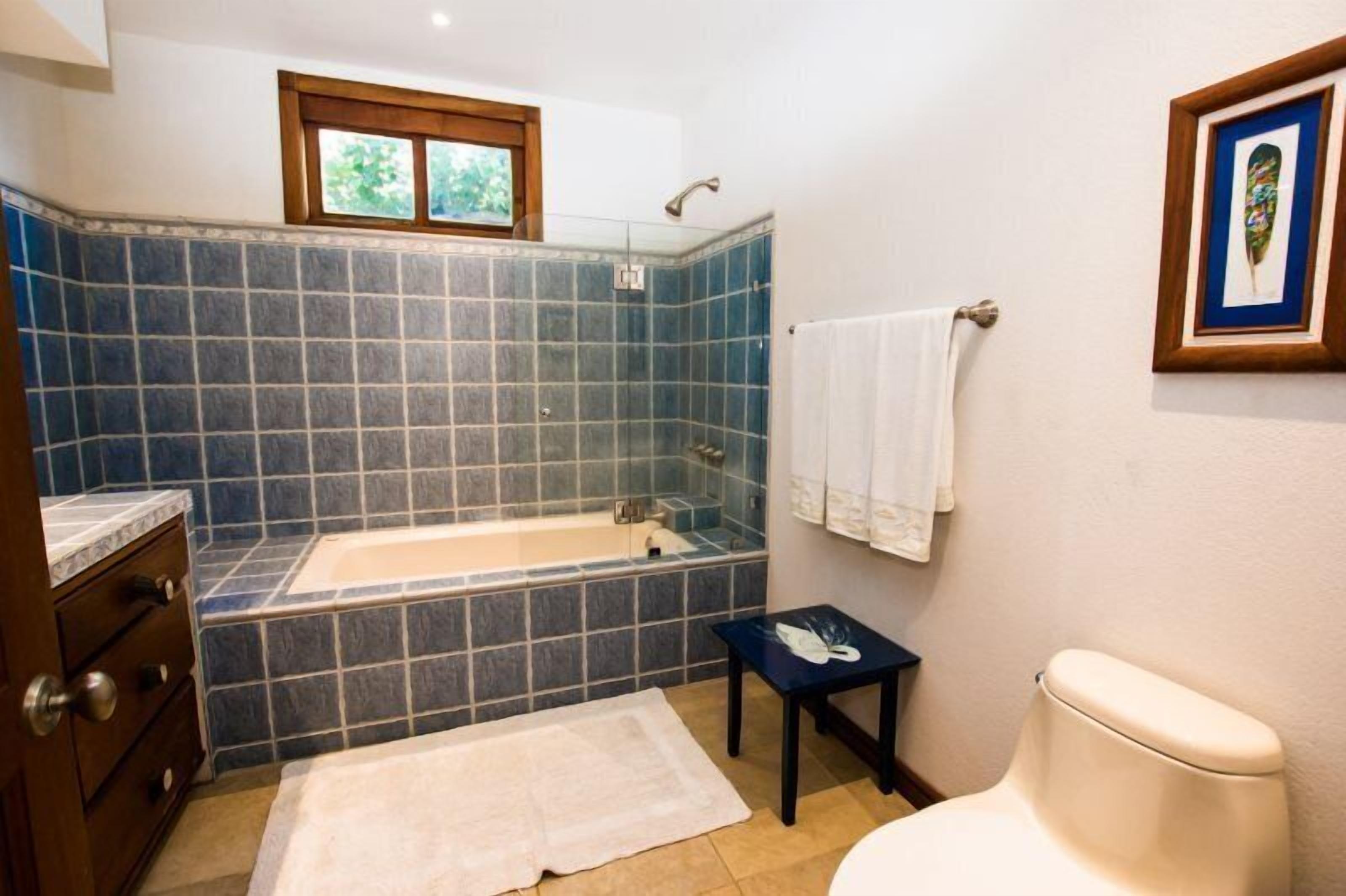A bathroom with a bathtub, a toilet, a sink, and a small table with towels.
