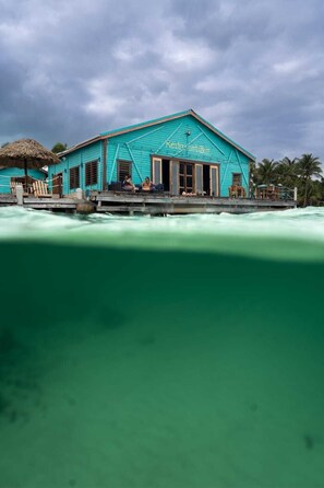 A turquoise building with a sign that reads 'Restroom Bar' on a wooden dock extending into turquoise water. - Tranquility Bay Resort (San Pedro)