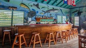 Un bar con taburetes de madera y una barra que muestra botellas.