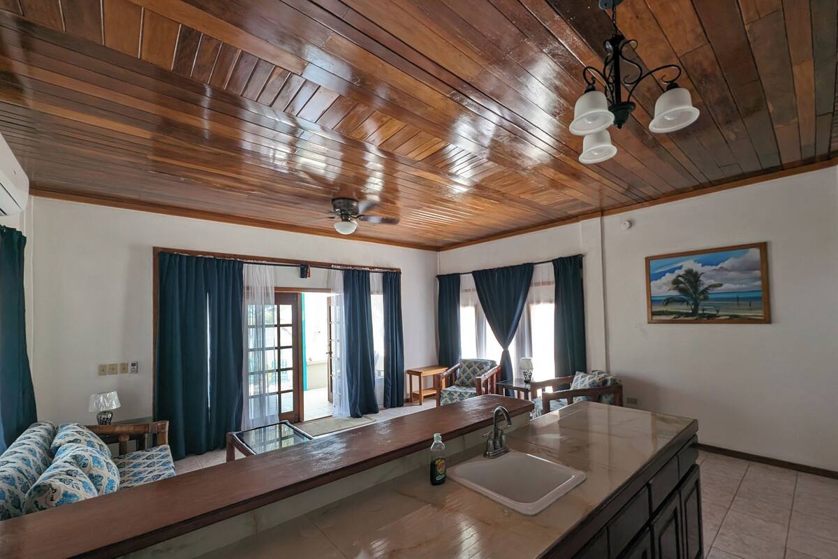 A spacious kitchen with a large island, wooden ceiling, and a painting of a beach scene.