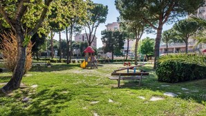 Un parque con juegos infantiles, una mesa de picnic y árboles.