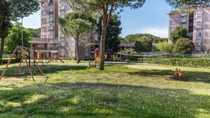 Zona residencial con un parque infantil, árboles y edificios de apartamentos al fondo.