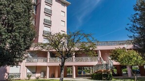 Un edificio rosa de varios pisos con balcones y un corredor cubierto.
