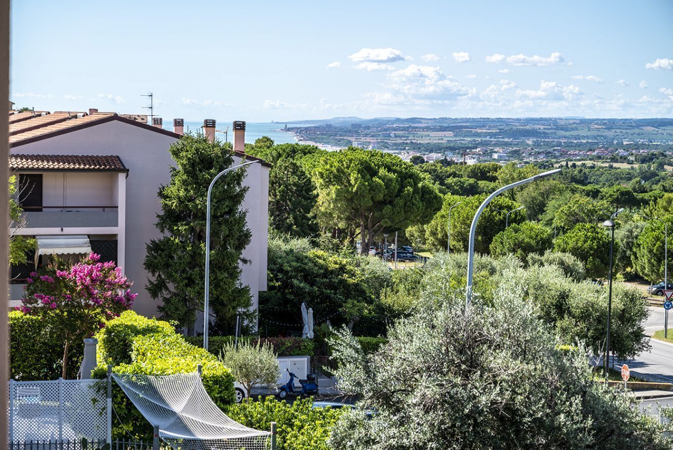 A residential area with a white building, trees, and a clear view of the landscape.