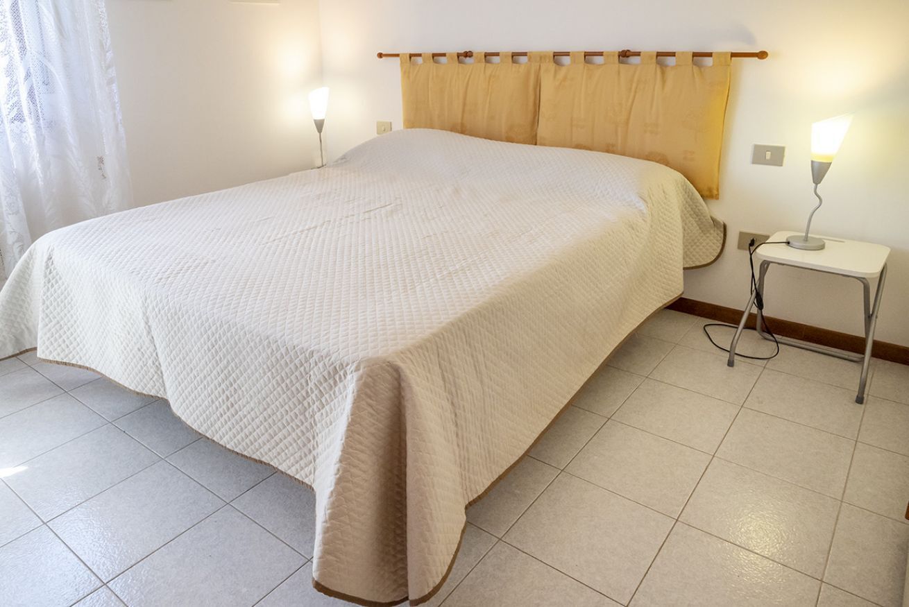 A neatly made bed with a headboard, a bedside lamp, and a small table with a lamp.