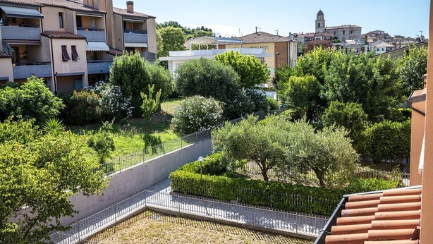 A residential area with multi-story buildings, a paved pathway, and lush greenery. - S220 - Sirolo, three-room apartment in the center with terrace (Sirolo)