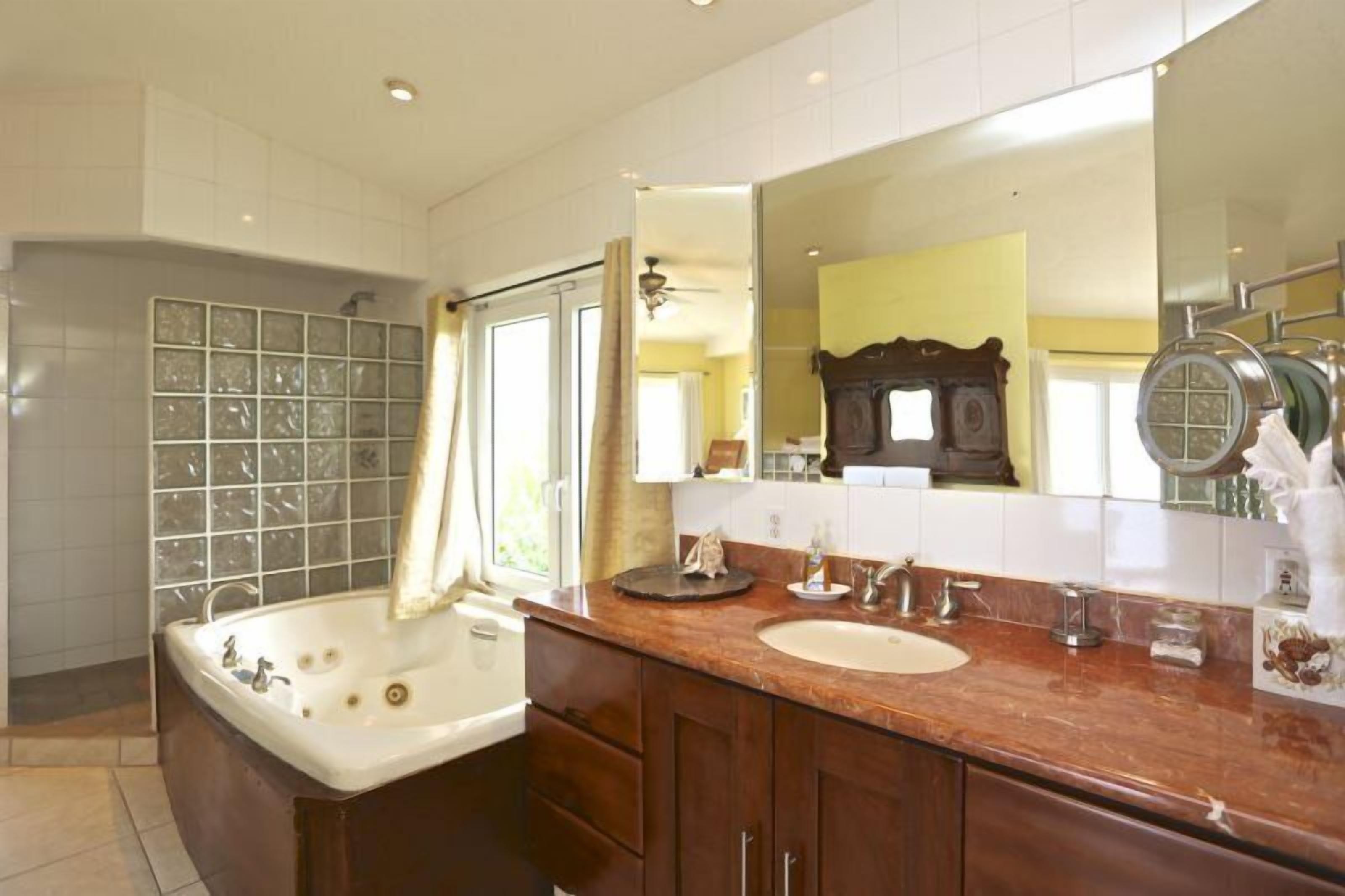 A bathroom with a large bathtub, a sink, and a mirror.
