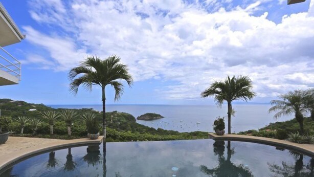 An infinity pool with a view of the sea and palm trees. - Villa Cielo Azul (Sardinal)