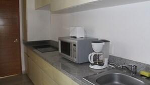A kitchen with a microwave, coffee maker, and sink.