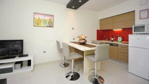A modern kitchen with a dining area, a TV, and a painting on the wall. - Apartment Antea (Split)