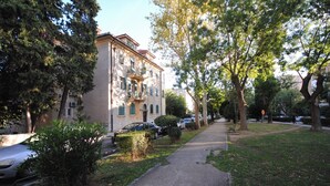 A residential building with a paved driveway, parked cars, and a sidewalk. - Apartment Antea (Split)