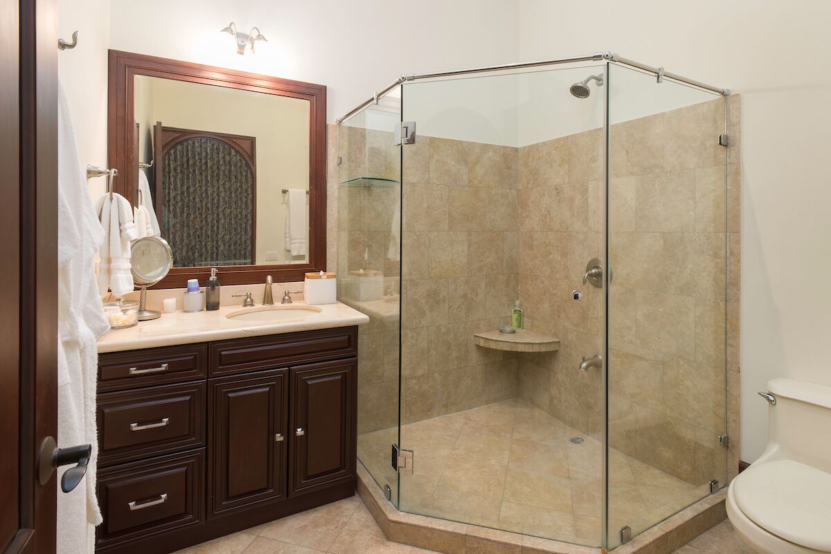 A bathroom with a glass-enclosed shower, a vanity with a mirror, and a toilet.