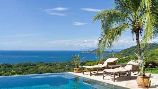 An infinity pool with a clear view of the ocean and hills. There are lounge chairs and potted plants. - Cinco Sinsotes (Sardinal)