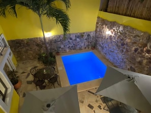 A small outdoor pool area with a stone wall and a yellow wall in the background. - Los Candiles (Valladolid)