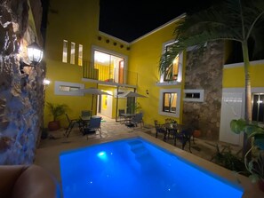 A yellow building with a swimming pool, outdoor seating, and a stone wall. - Los Candiles (Valladolid)
