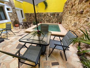 Un patio con una mesa de vidrio, sillas y una piscina pequeña.