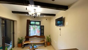 A living room with a wooden bench, a TV mounted on the wall, and a ceiling fan. - Los Candiles (Valladolid)