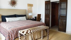 A bedroom with a bed, a bench, a wall decoration, a lamp, and a wardrobe. - Casa Oso Grande (Sardinal)