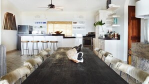 A modern kitchen with a dining area featuring a dark wooden table and fur-covered chairs. - Casa Oso Grande (Sardinal)