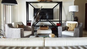 A living room with wicker furniture, a television, and a decorative fish on the wall. - Casa Oso Grande (Sardinal)