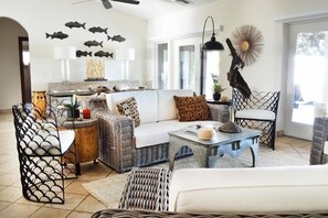 Una sala de estar con muebles de mimbre, un sofá blanco y una mesa de centro.
