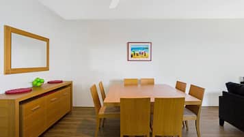 Un comedor con una mesa y sillas de madera, un armario de madera con cajones y un cuadro enmarcado en la pared.