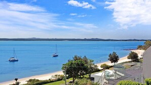 Une vue sur la côte, avec une plage, des voiliers et un ciel dégagé.